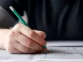 Dłoń z ołówkiem pisze po kartce. Zastanawiam się, ile jest punktów na maturze z angielskiego.