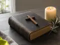 Stara biblia z krzyżem i płonącą świecą, symbol przygotowań do matury z wiedzy duchowej.