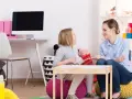 Terapeutka wspiera dziewczynkę w terapii afazji u dzieci, pracując nad komunikacją i rozwojem mowy.