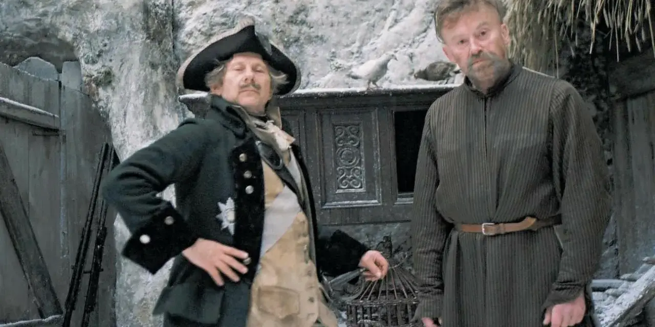 Dwóch mężczyzn w historycznych strojach, jeden w mundurze z epoki, drugi w prostej tunice. Scena jak z filmów do matury, zimowa sceneria.