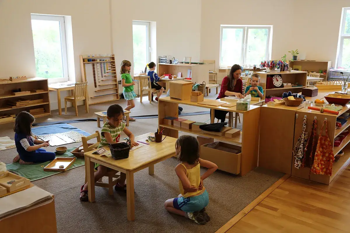 Dzieci uczą się przez zabawę i samodzielność, co pokazuje metoda Montessori na czym polega. W klasie panuje spokój i skupienie.